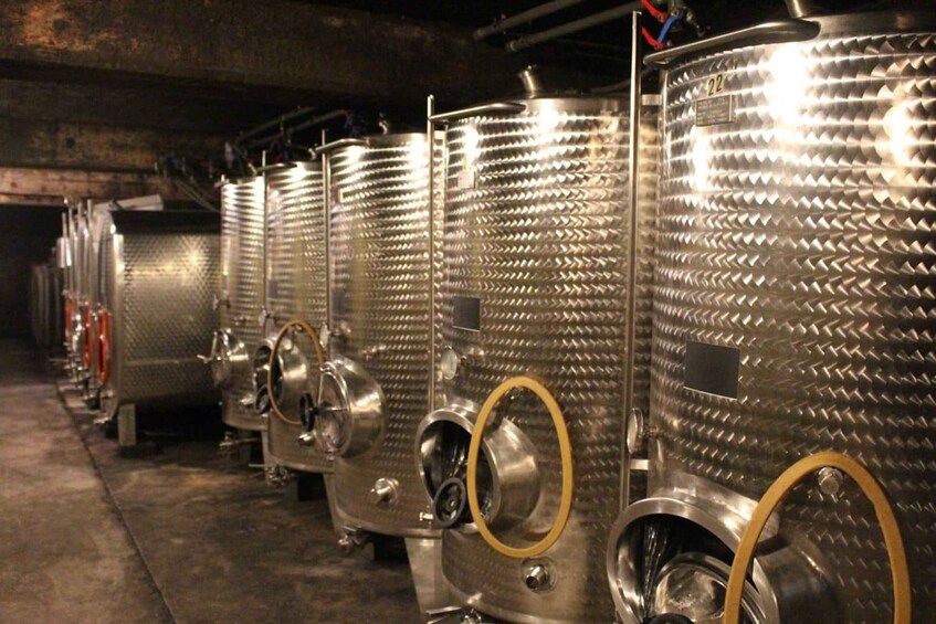 A row of stainless steel fermentation tanks with circular openings, likely used for brewing or distilling. 3