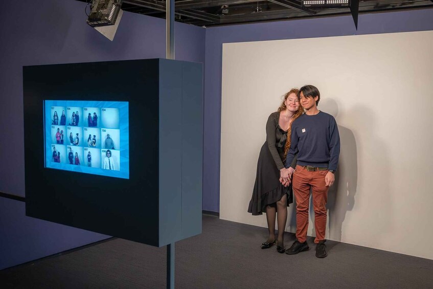 A digital display with multiple photos, a dark-colored stand, and a plain wall in the background. 2