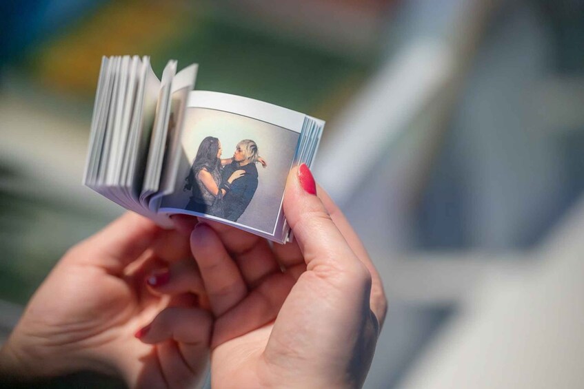 A person holding a small photo album with a picture of two people. 3