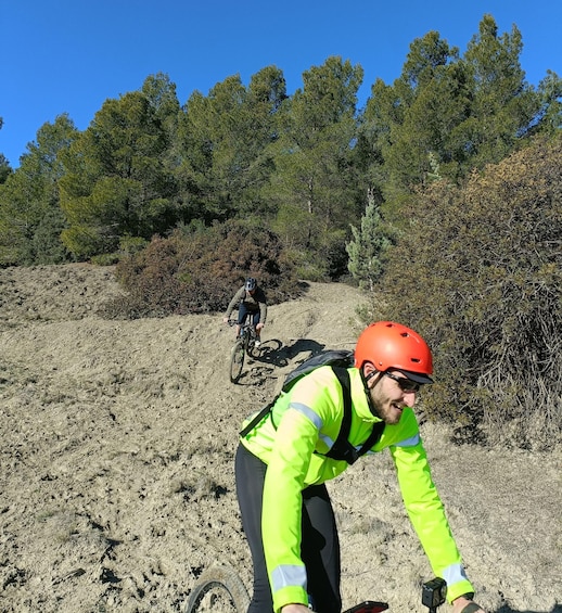 A person in a neon yellow jacket and red helmet on a mountain bike trail. 4