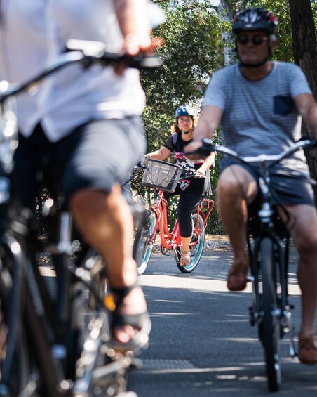 People riding bicycles on a road with trees in the background. 3