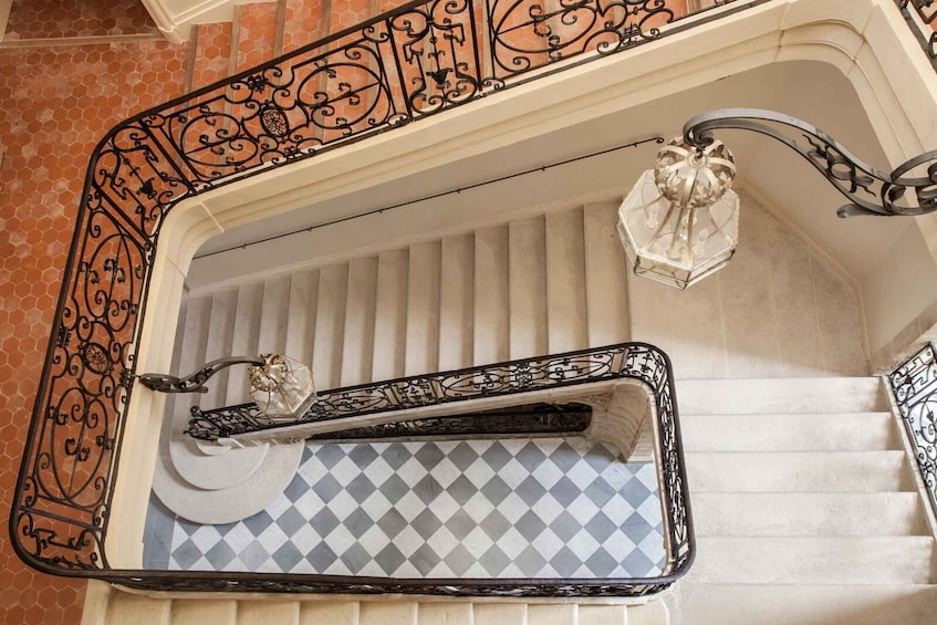 A staircase with ornate black metal railings, a patterned blue and white floor, and a decorative lantern. 4