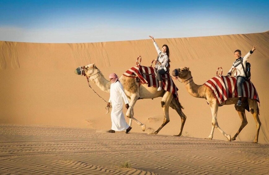 Three camels with riders in a desert landscape. 2