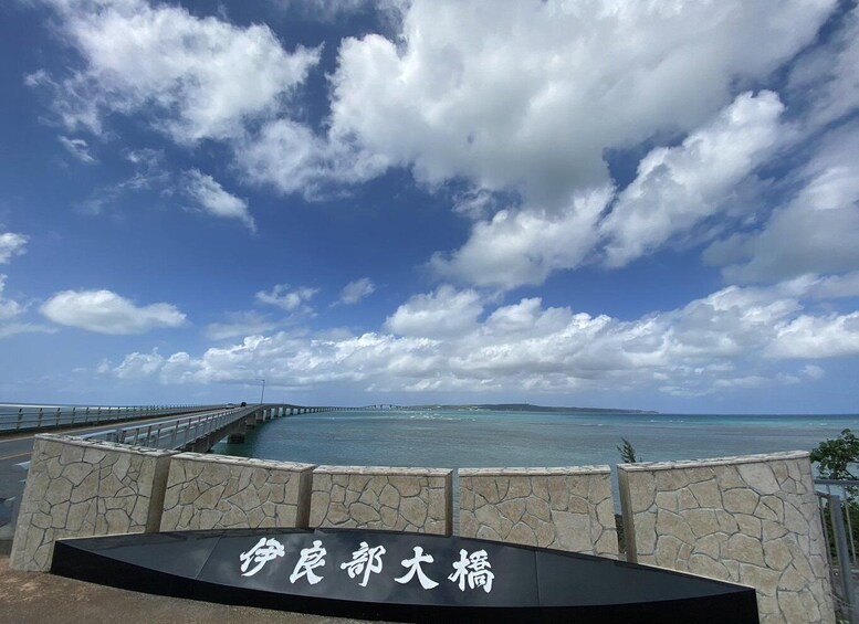 A coastal road with a stone wall and a sign with Chinese characters. 4