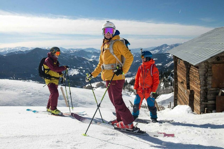 Three skiers on a snowy mountain with a wooden cabin in the background. 5