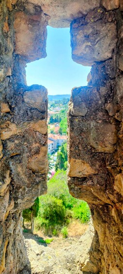 A stone archway with a view of a town and greenery below. 5