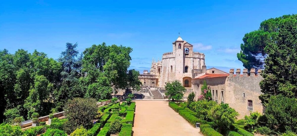A historic building with a bell tower, surrounded by well-manicured gardens and trees. 1