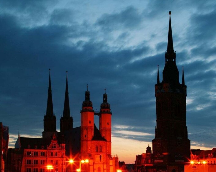 A cityscape at dusk with prominent church spires and illuminated buildings. 3