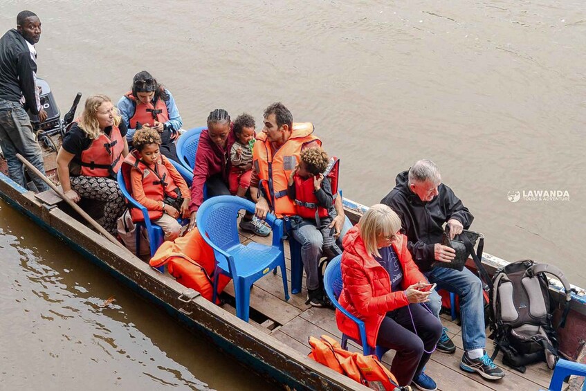 A group of people on a boat, some wearing life jackets, with a calm body of water in the background. 5