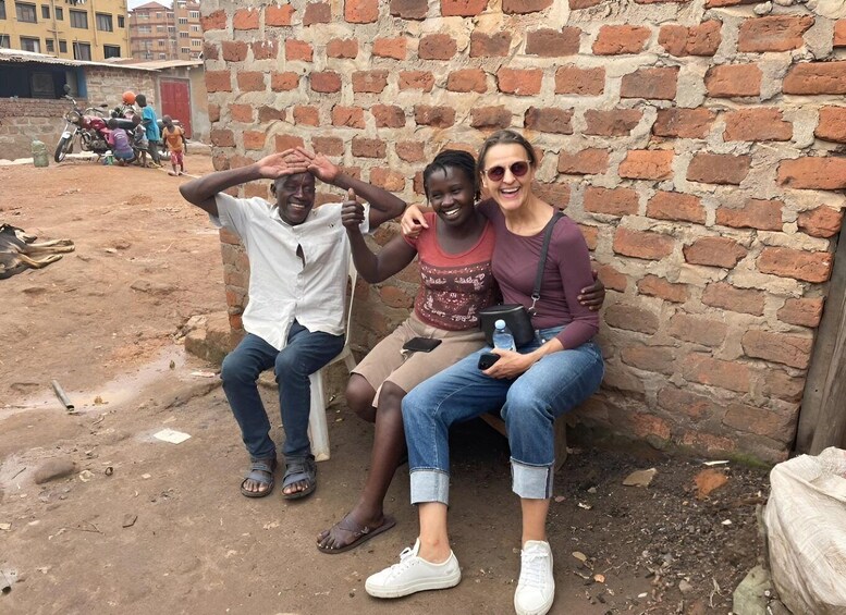 Two people sitting on a bench against a brick wall, with a motorcycle and children in the background. 2