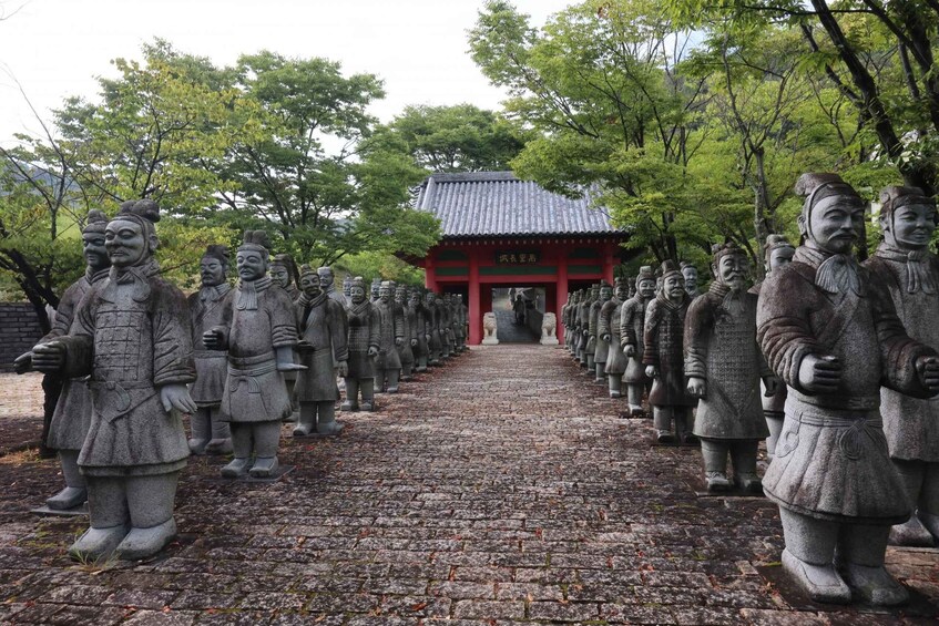A row of stone statues of historical figures lined up in front of a traditional red building. 4