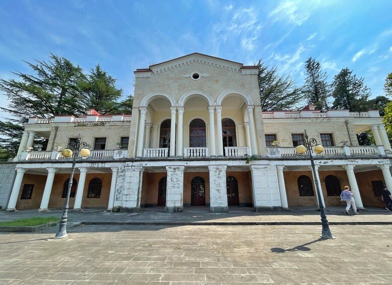 A historic building with a central archway, columns, and a balcony with decorative elements. 2