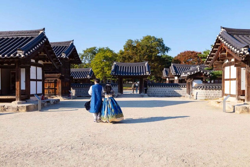 A traditional Korean gate with a couple dressed in historical attire walking through. 2