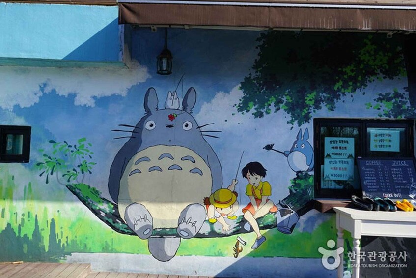 A mural of Totoro, a character from Studio Ghibli's film, with two children and a dog. 5