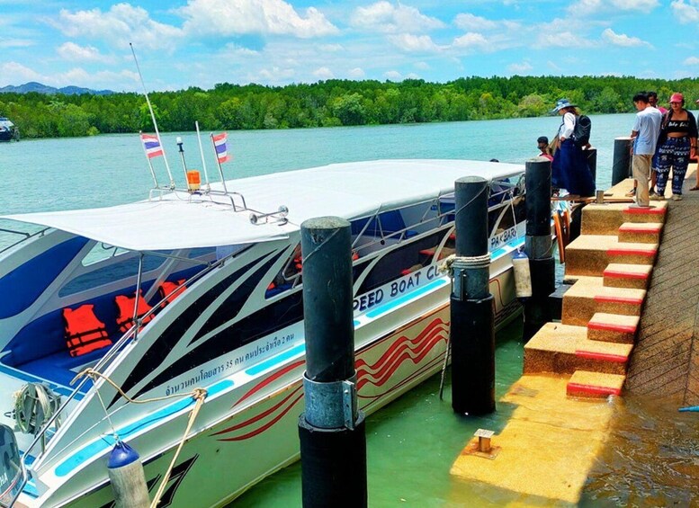 A speed boat docked at a pier with people boarding. 5