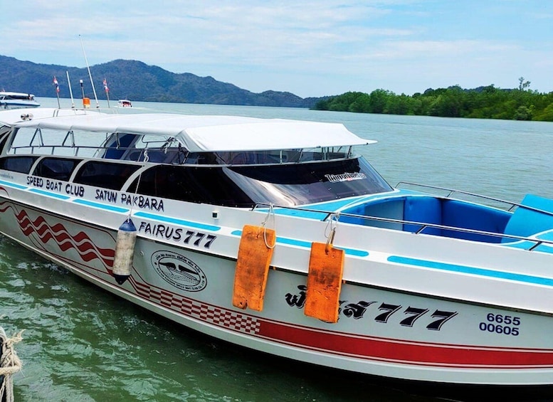 A speed boat named 'FAIRUS 777' docked at a marina with mountains in the background. 1