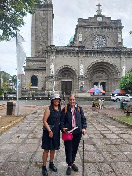 Two people standing in front of a historic church with a clock tower. 4