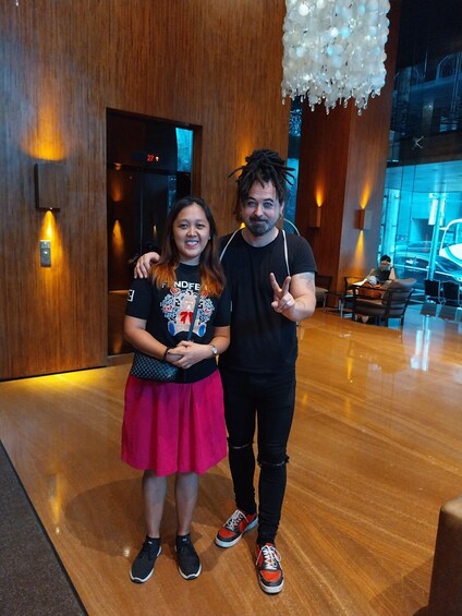 Two people standing in a modern interior space with wooden flooring and a decorative white chandelier. 3