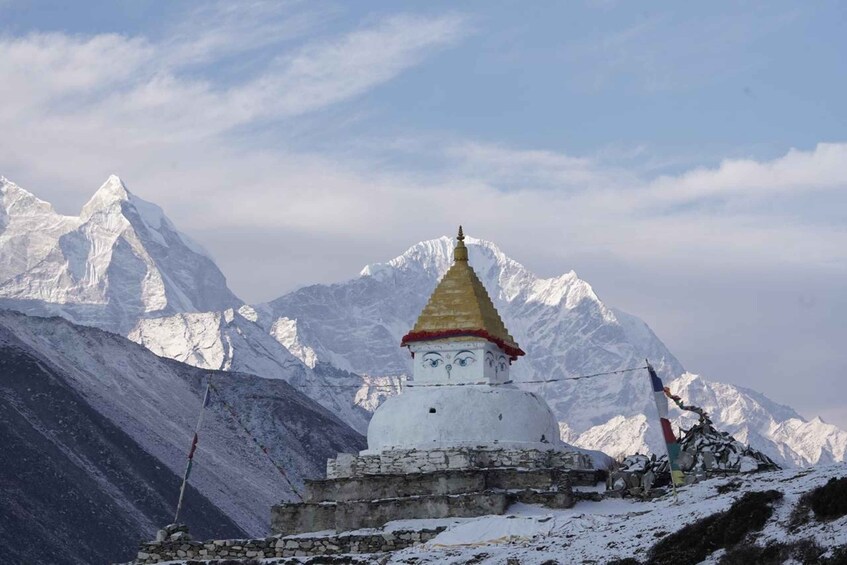 A snow-covered mountain with a white stupa and a golden spire, surrounded by snow-capped peaks. 2