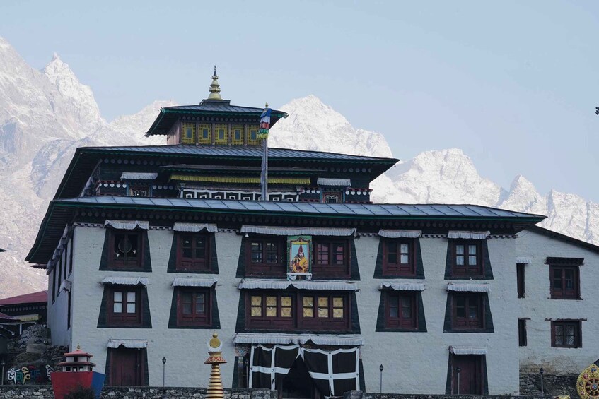 A traditional multi-tiered building with a flag, set against a backdrop of snow-capped mountains. 3