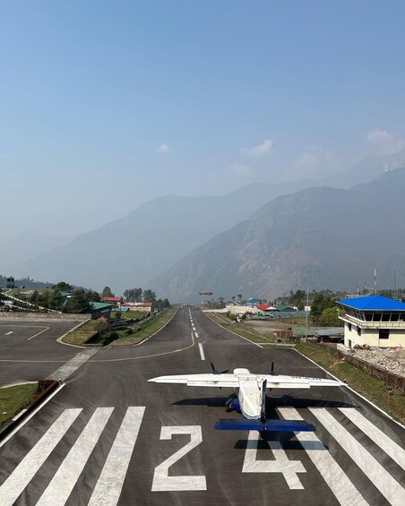 An airplane on a runway with mountains in the background. 5