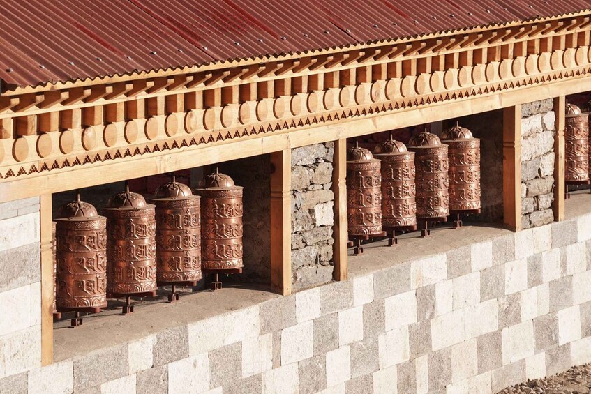 A traditional building with a corrugated metal roof and a series of prayer wheels. 4