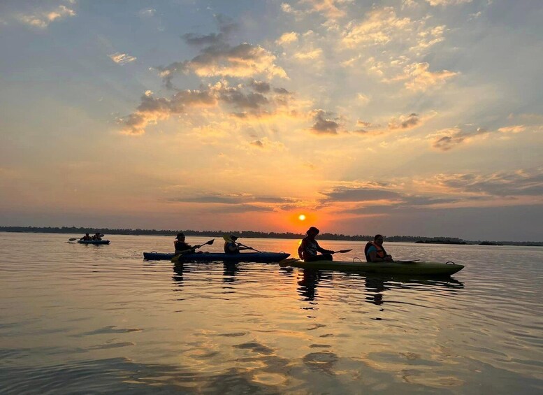 A group of people kayaking on a calm body of water during sunset. 2