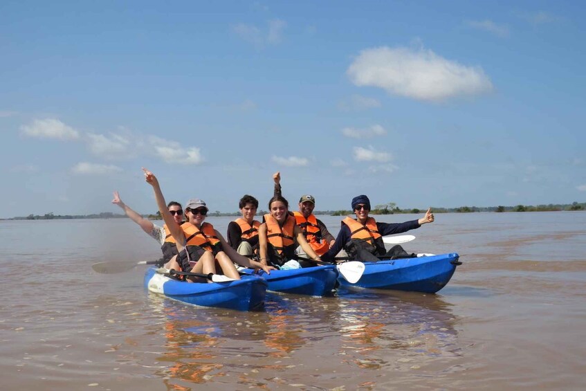 A group of people in a blue boat on a calm body of water, wearing life jackets. 5