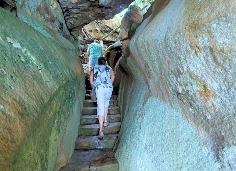 A person climbing a narrow stone staircase between large rock formations. 2
