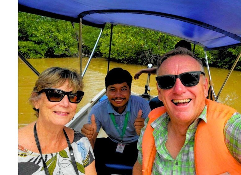 Three people on a boat with a canopy, surrounded by greenery and water. 1