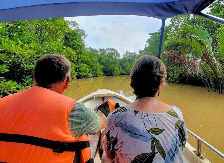 Two people on a boat in a river surrounded by dense greenery. 5