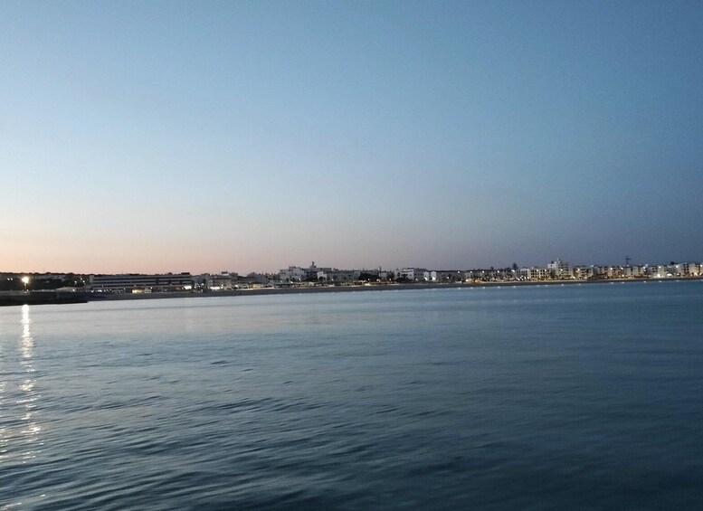 A calm waterfront with buildings along the shore and a clear sky. 2
