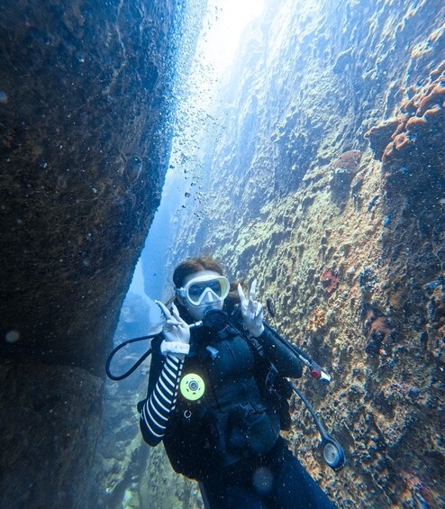 A diver underwater in a narrow canyon with rocky walls. 2