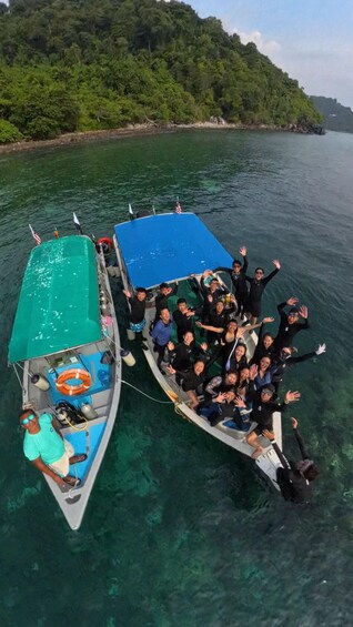Two boats with people on them, surrounded by clear water and a forested island in the background. 5