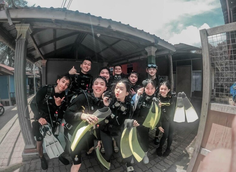 A group of people in scuba diving gear posing under a covered area. 4