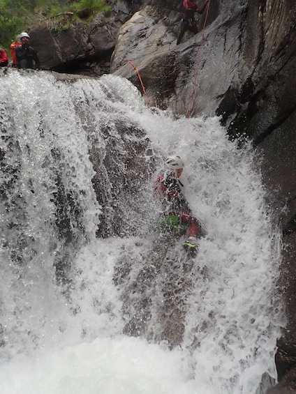 A person navigating a turbulent waterfall with a helmet and life jacket. 3