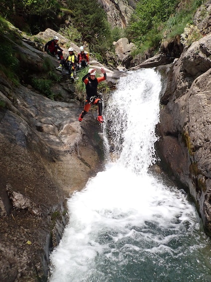A person rappelling down a waterfall in a rocky canyon. 1