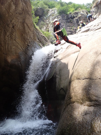 A person jumping off a rock into a waterfall. 4