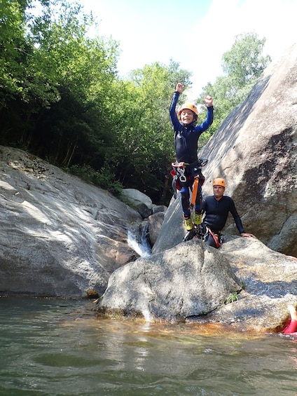 Two people rappelling down a rocky cliff into a river. 5