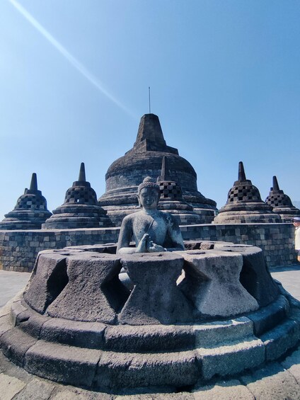 A stone Buddha statue in front of a temple with multiple pagodas. 3