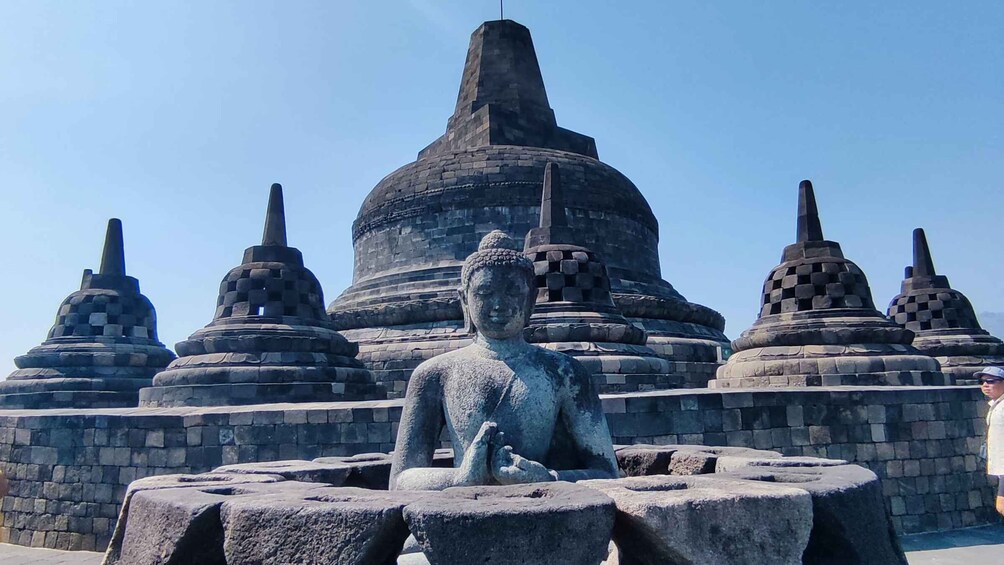 A large Buddha statue in front of a temple with multiple pagodas. 5