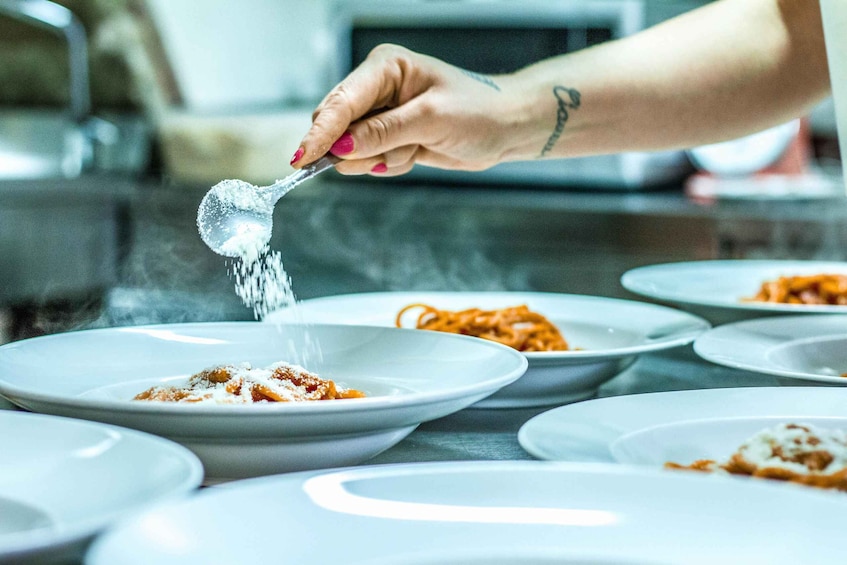 A person sprinkling salt over a dish of food. 3