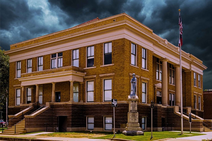 A historic building with a statue in front, under a stormy sky. 3