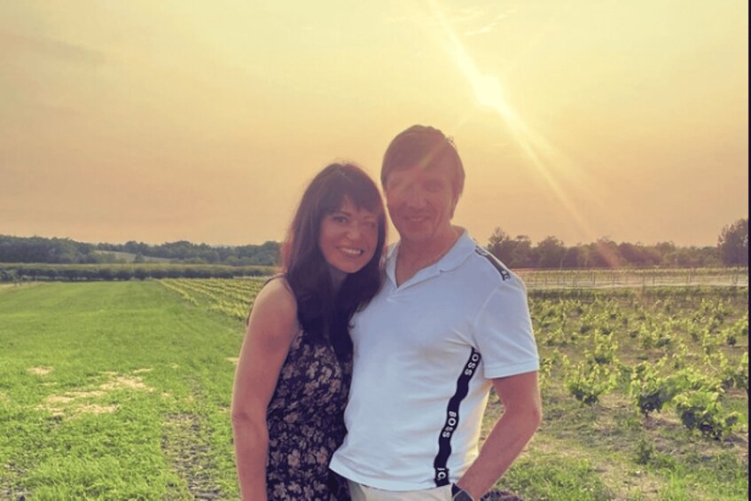 A person standing in a field with a vineyard in the background. 5