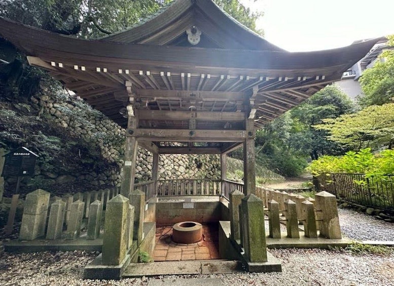 A traditional Japanese torii gate with a stone base and wooden pillars, surrounded by a gravel path and lush greenery. 1