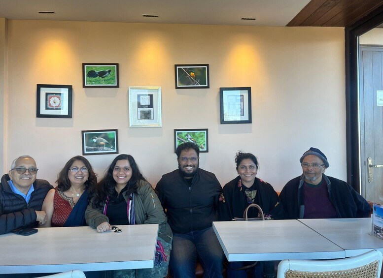A group of people seated at a table in a room with framed pictures on the wall. 5