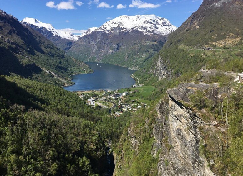 A mountainous landscape with a lake, a small settlement, and snow-capped peaks. 3