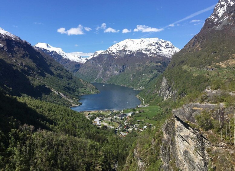 A mountainous landscape with a lake, snow-capped peaks, and a small settlement. 5