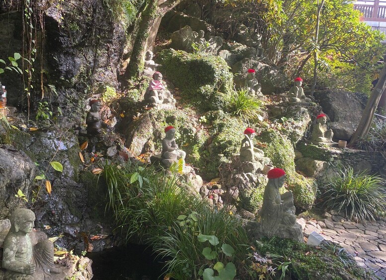 A garden with stone statues, some wearing red hats, surrounded by greenery and rocks. 4