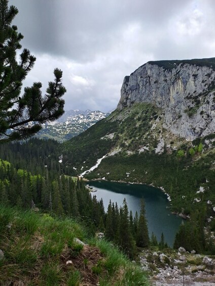 A mountainous landscape with a lake, dense forests, and rocky cliffs. 5